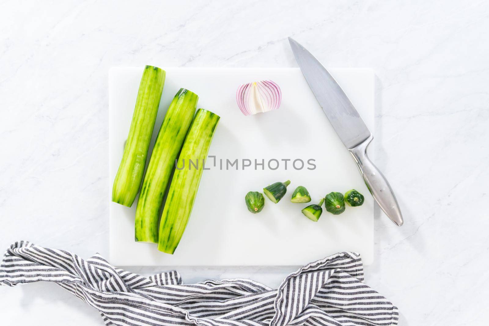 Flat lay. Cutting ingredients on a white cutting board to make summer cucumber salad.