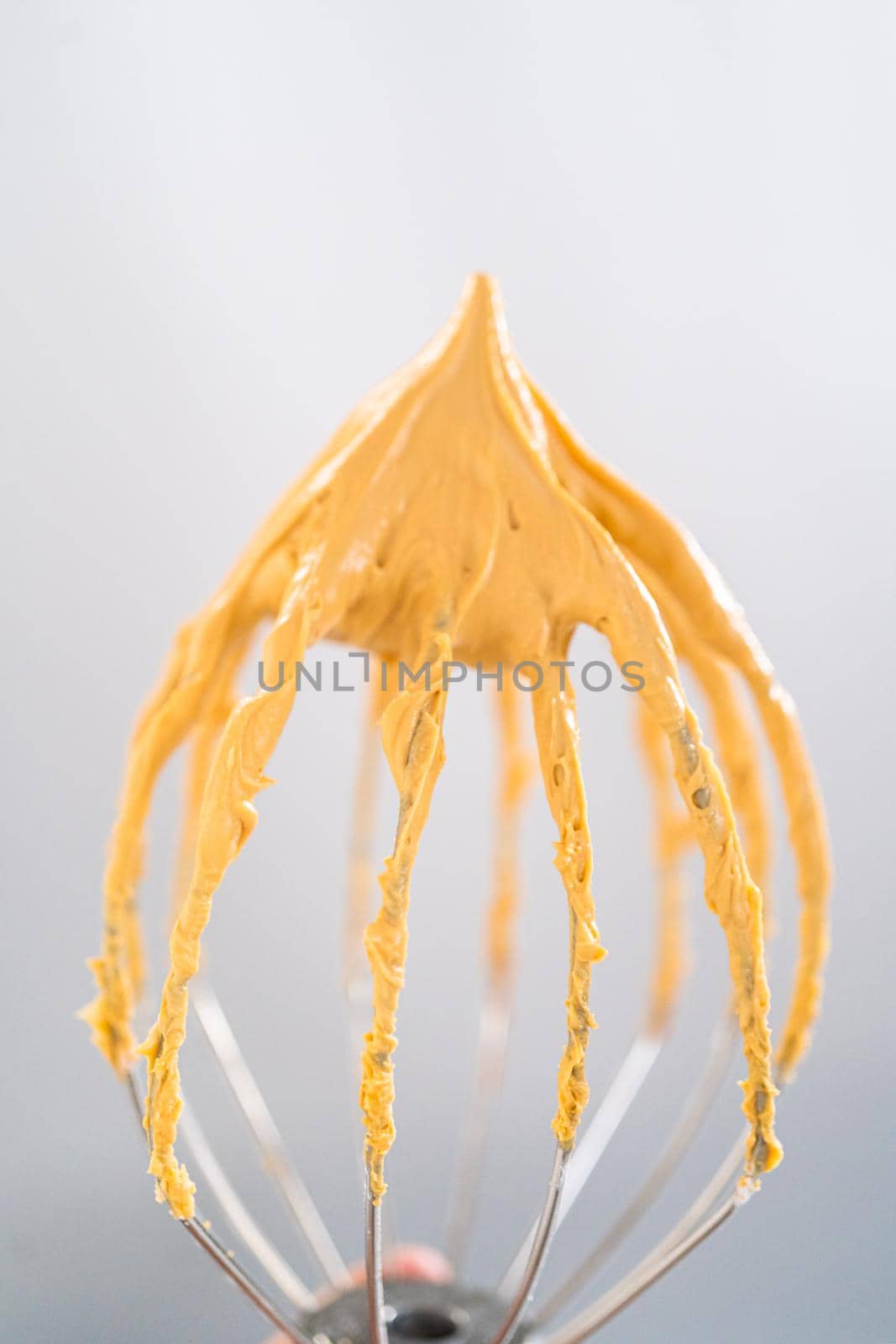 Freshly whipped dulce de leche buttercream frosting on a whisk.