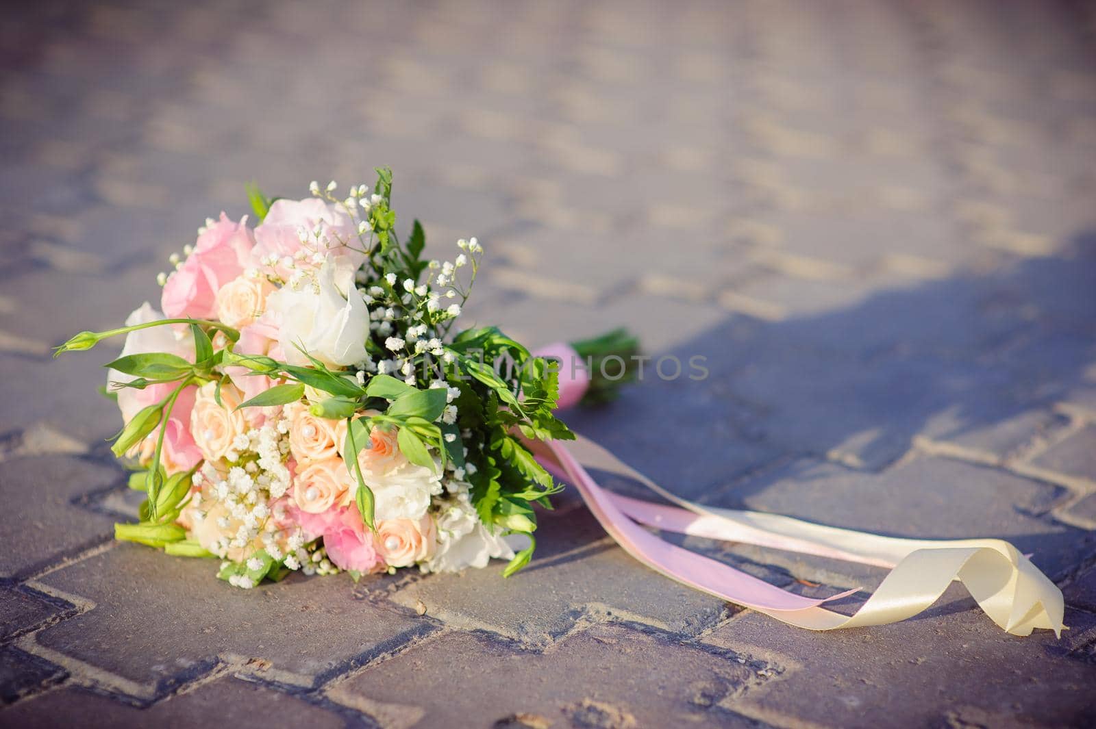 Bridal wedding bouquet of flowers. Wedding bouquet of yellow and white roses lies on the concrete floor.