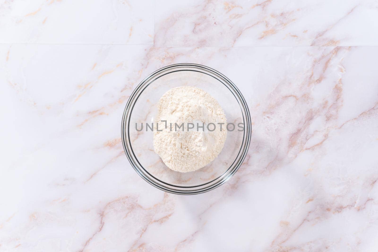 Flat lay. Mixing ingredients in a large glass mixing bowl to bake apple sharlotka muffin.