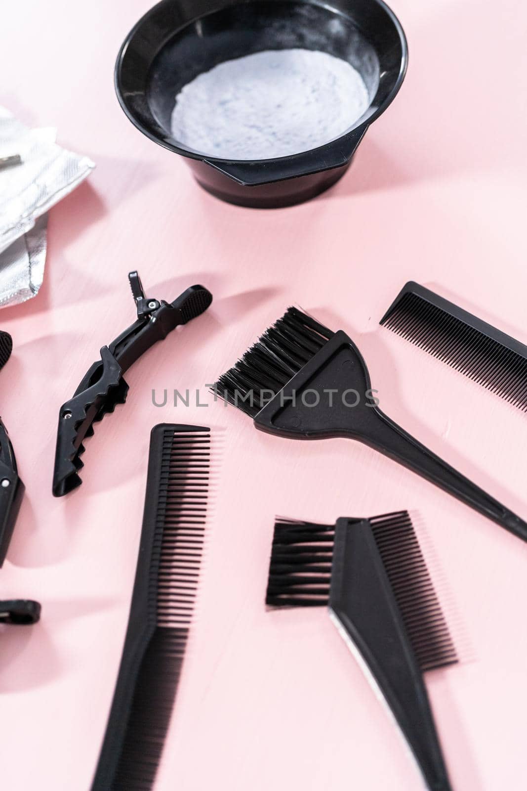 Hair color dye powder in a black plastic mixing bowl on a pink background.