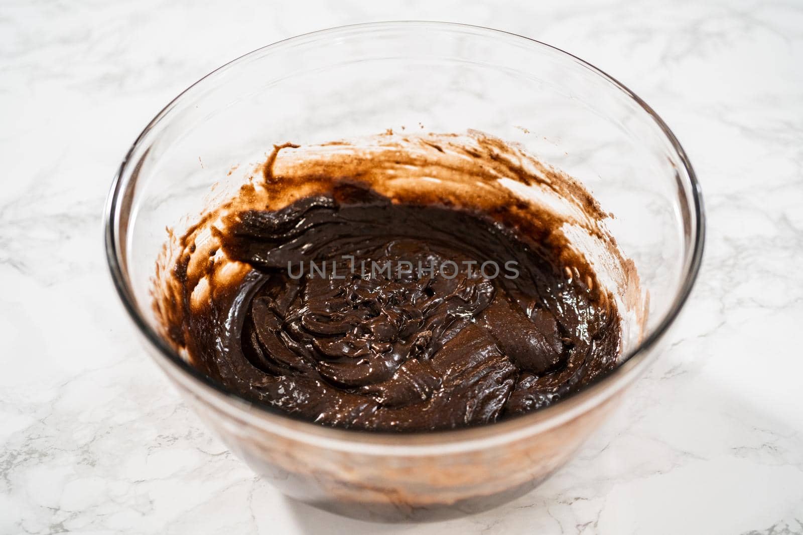 Mixing ingredients in a large glass mixing bowl to bake chocolate peppermint cupcakes.