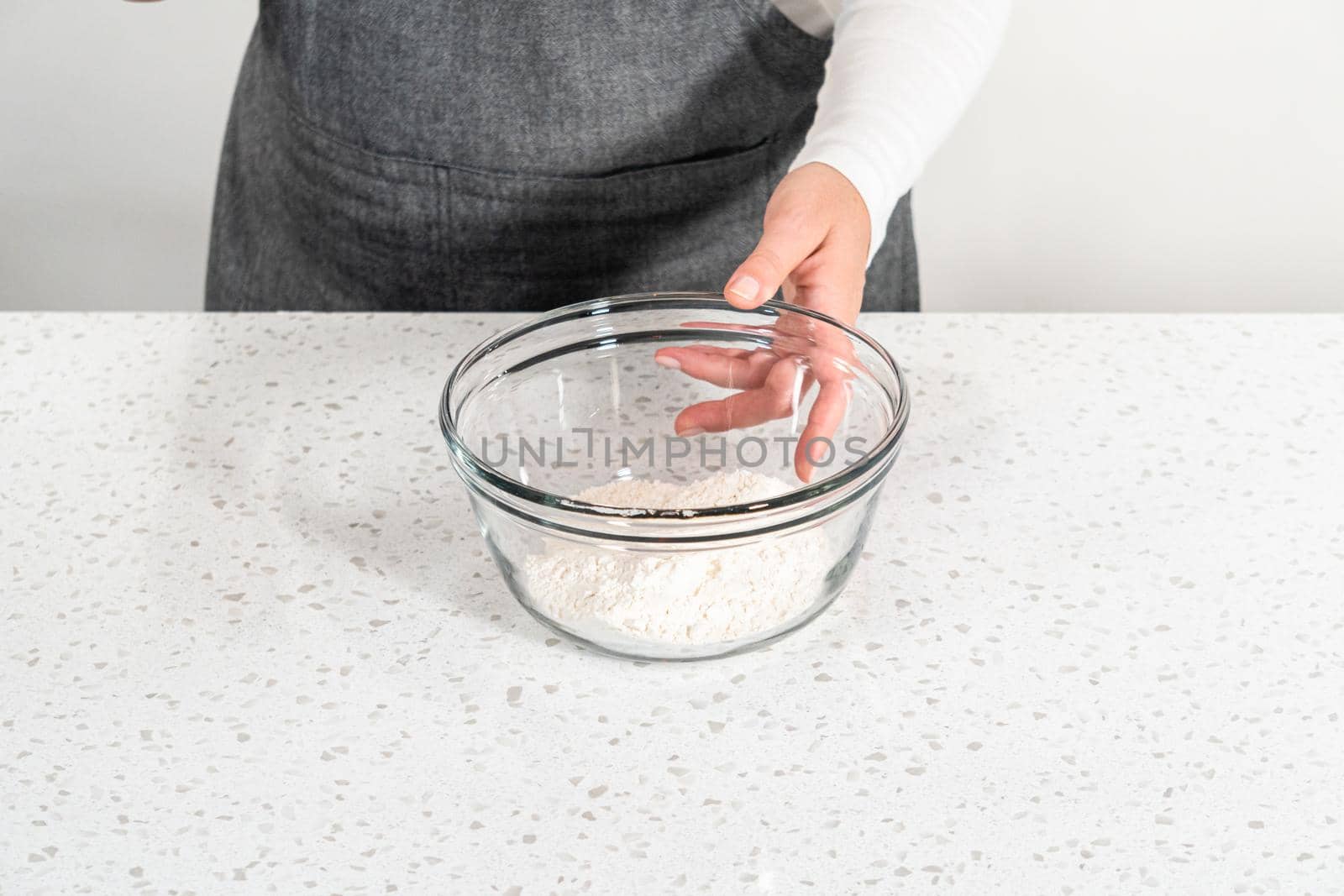 Mixing dry ingredients with a hand whisk in a large glass mixing bowl to bake dulce de leche cupcakes.