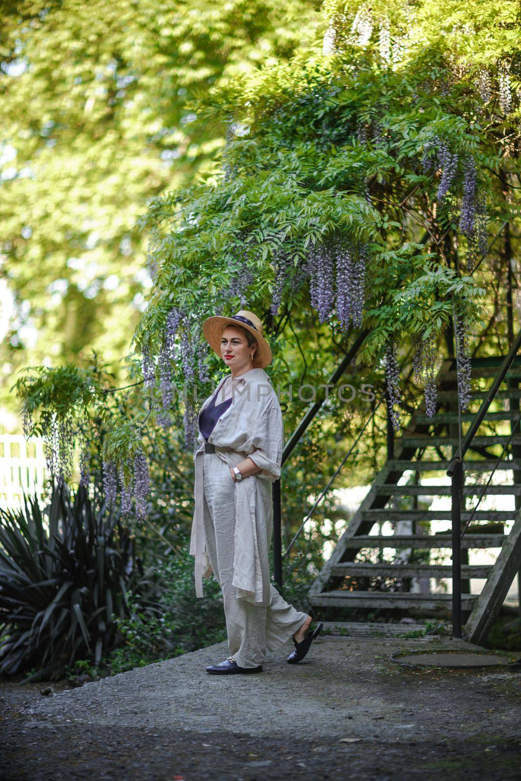 Thoughtful happy mature woman surrounded by chinese wisteria.