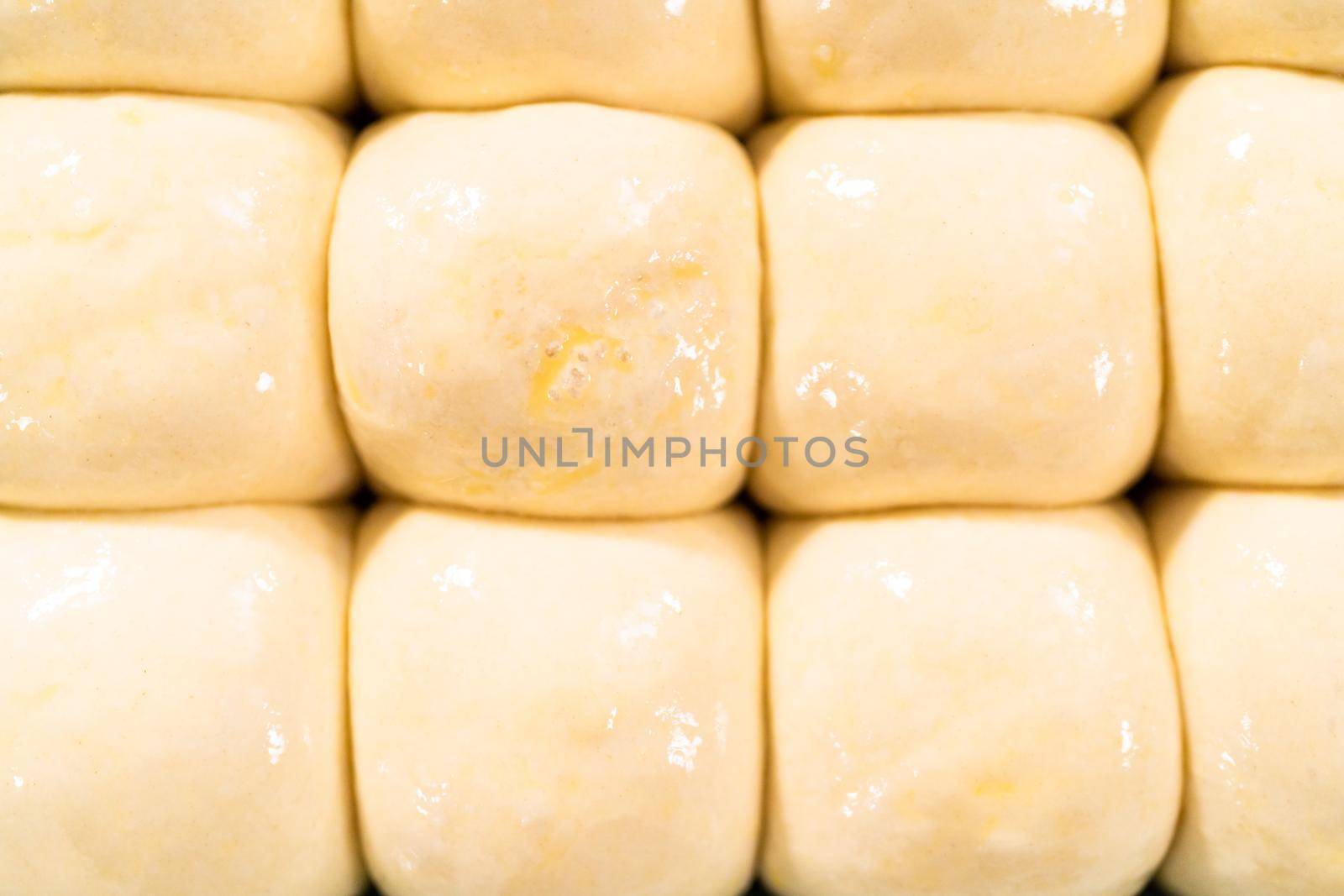 Brushing dinner rolls with mixture of egg and milk before baking in the baking pan.