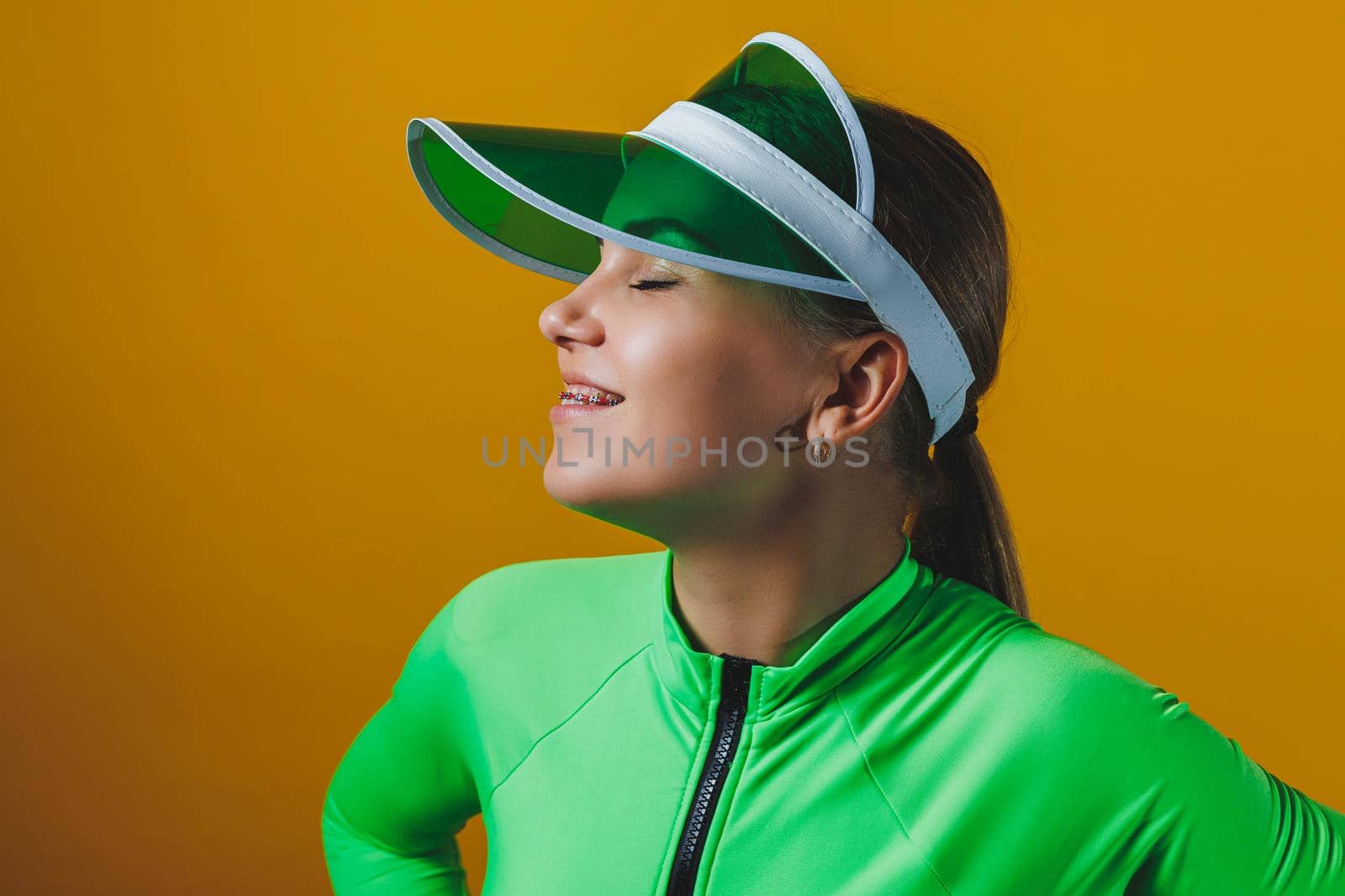 Attractive woman in bright green beach swimsuit, hat, on bright yellow background with perfect body. Isolated. Studio shot.