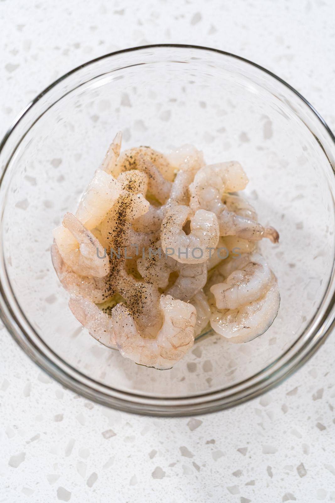 Seasoning raw shrimp to prepare shrimp scampi in the microwave.