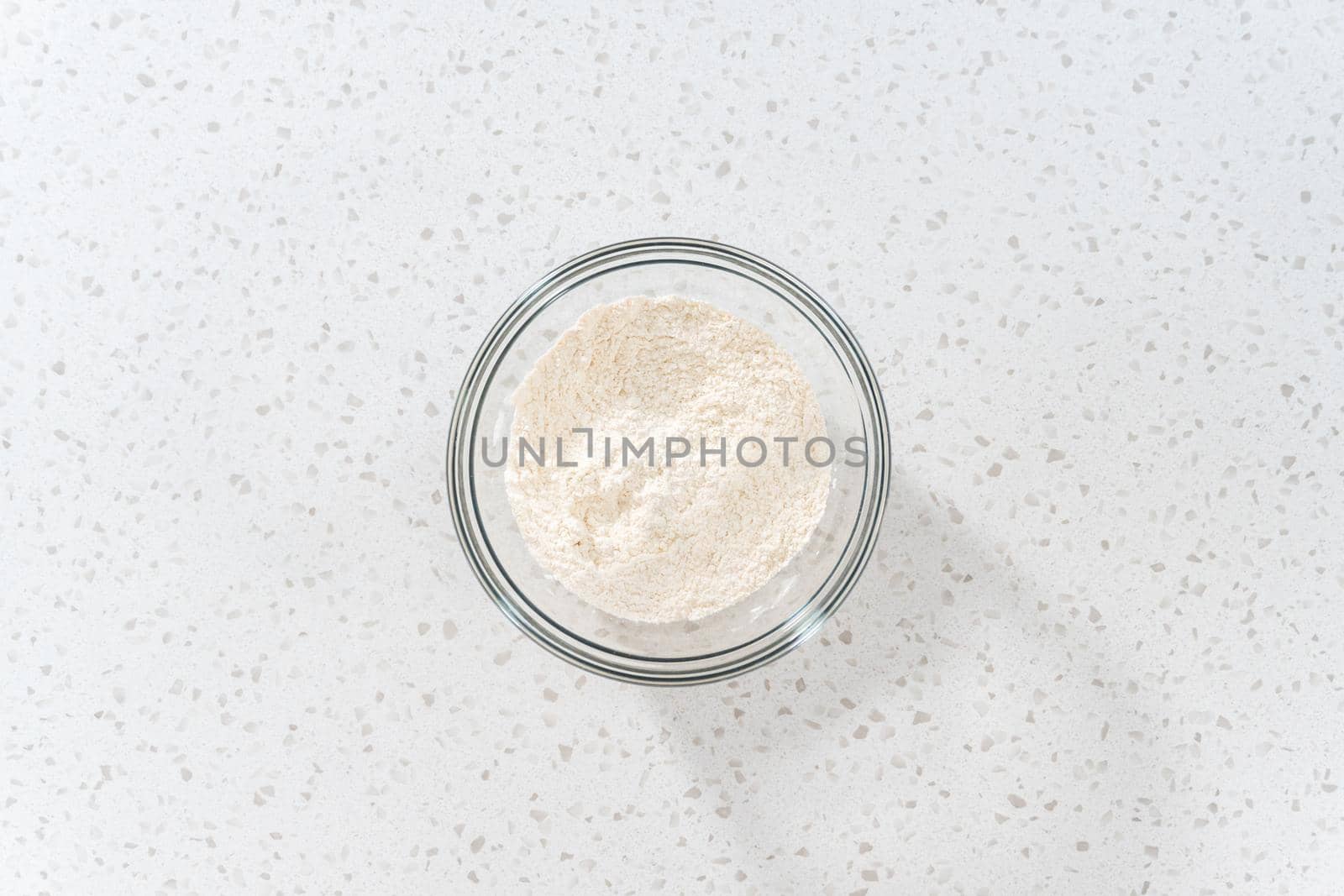 Flat lay. Mixing dry ingredients with a hand whisk in a large glass mixing bowl to bake dulce de leche cupcakes.