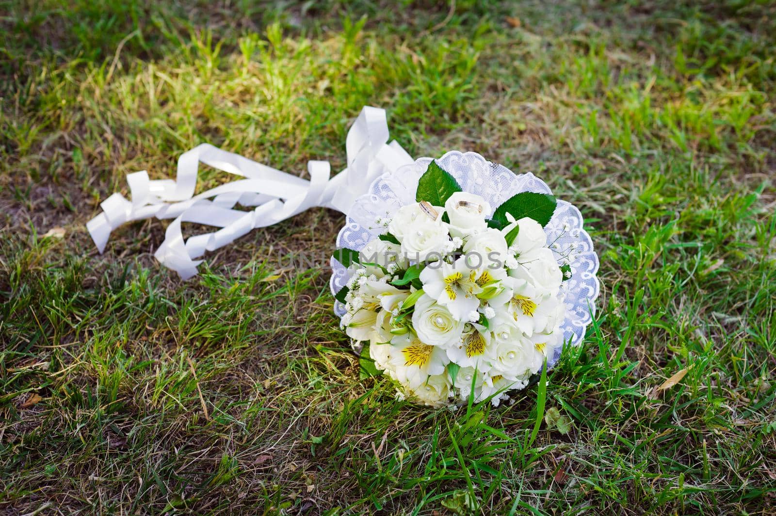 Bridal wedding bouquet of flowers. Wedding bouquet of yellow and white roses lying on a grass