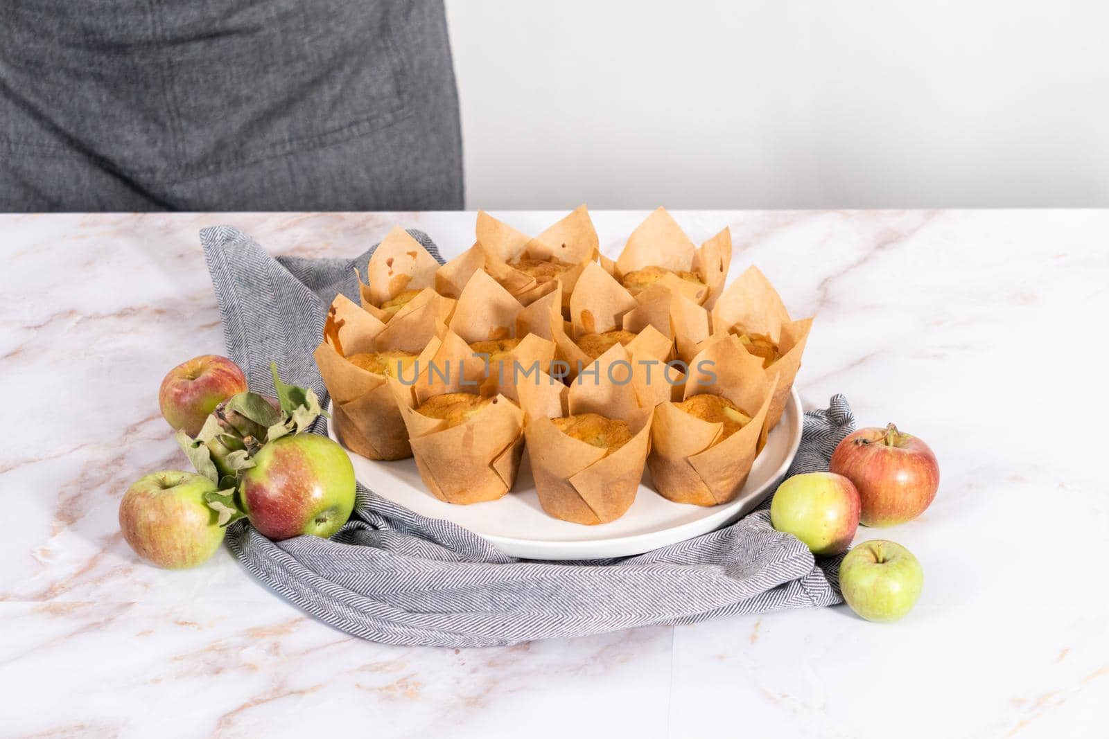 Garnishing freshly baked apple sharlotka muffins dusted with powdered sugar.