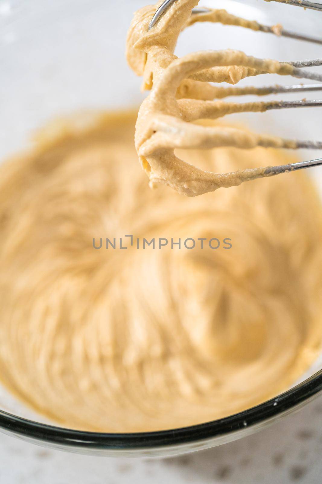 Mixing ingredients with a hand mixer in a large mixing bowl to bake dulce de leche cupcakes.