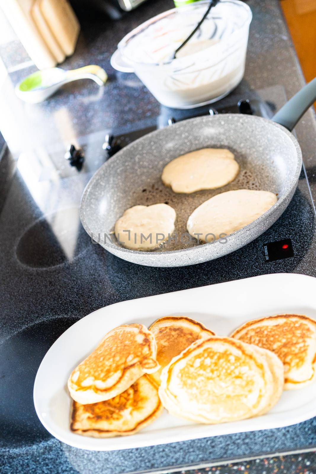 Frying kefir based pancakes in cooking pan on an electric stove.