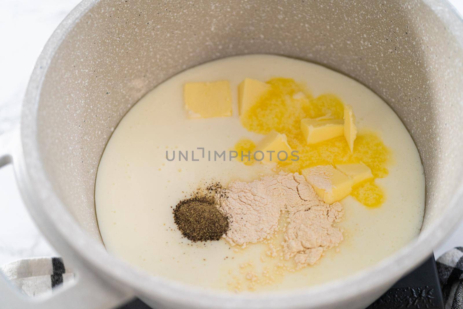 Cooking cheesy sauce in a cooking pot to prepare macaroni and cheese with broccoli.