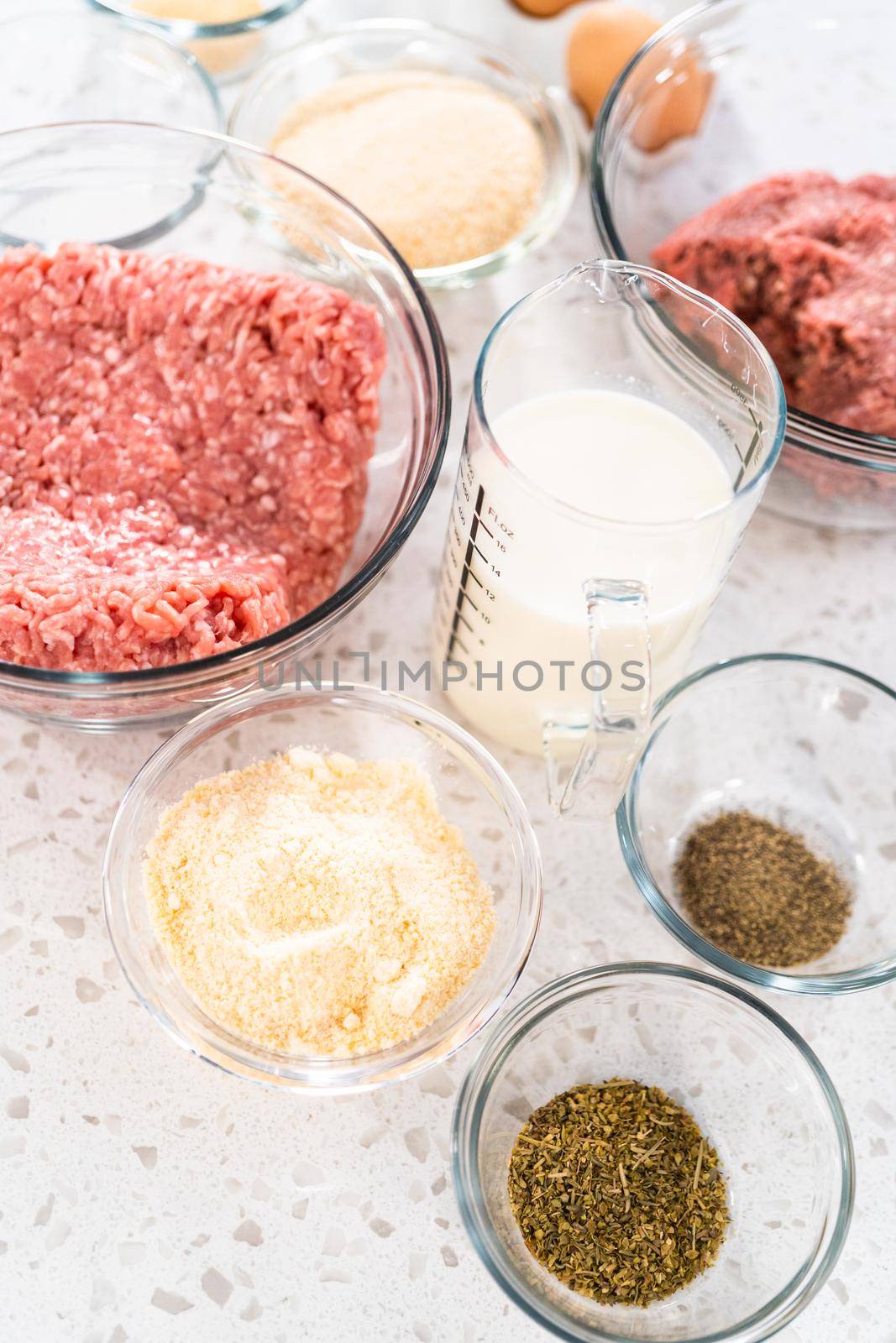 Measured ingredients in glass mixing bowls to make oven-baked meatballs.
