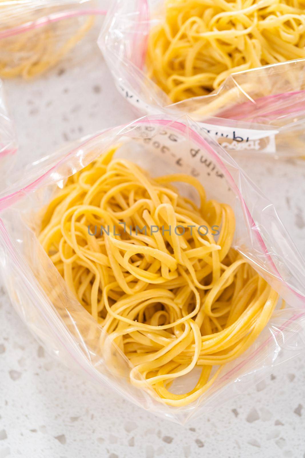 Packaging homemade frozen shrimp scampi meal prep into plastic resealable bags.