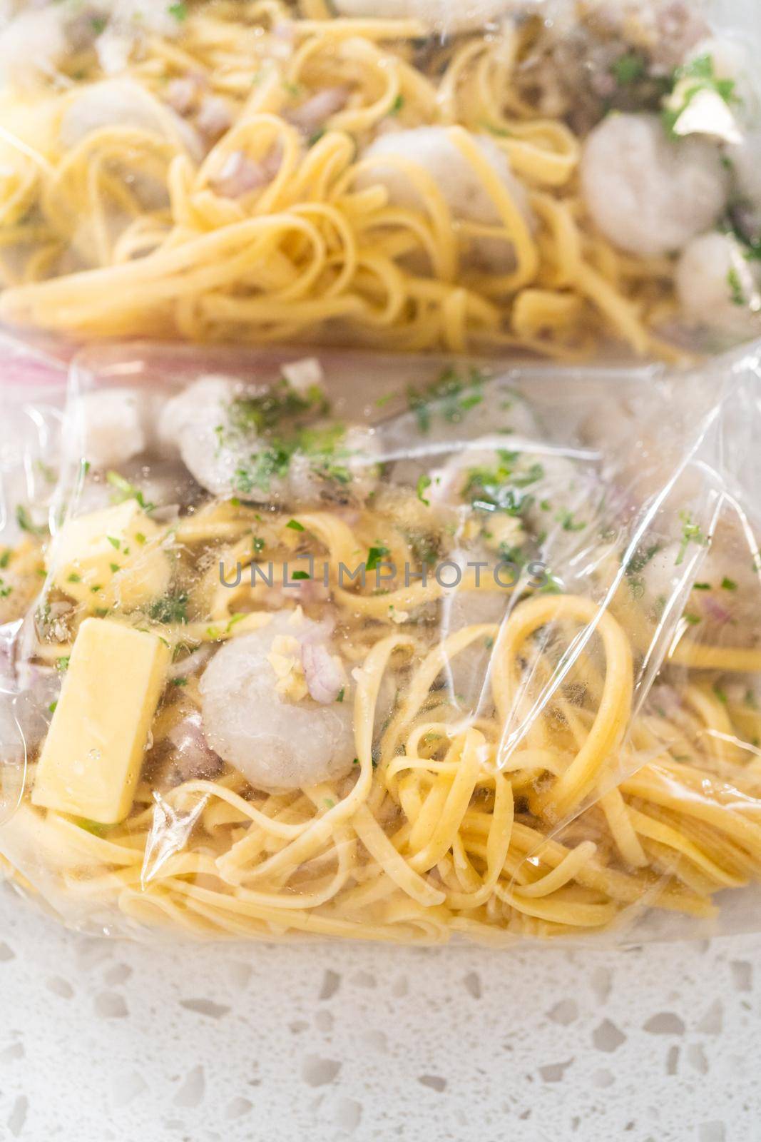 Packaging homemade frozen shrimp scampi meal prep into plastic resealable bags.