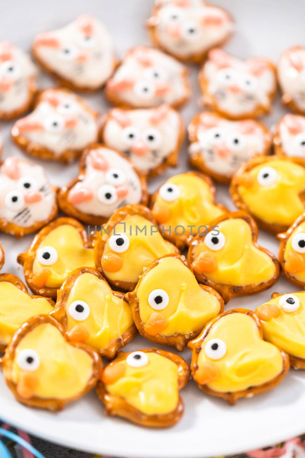 Easter chocolate-covered pretzel bunnies and ducklings on a white serving plate for the Easter table.