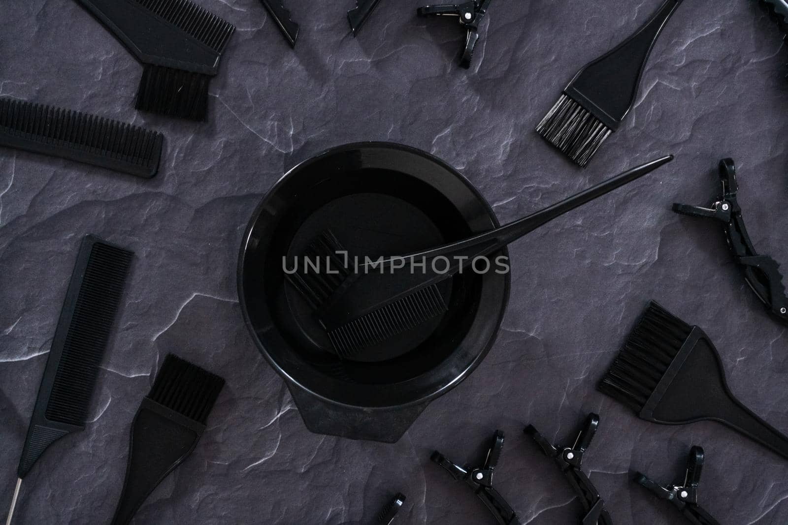 Flat lay. Black hair color dye kit with mixing bowl on a black background.