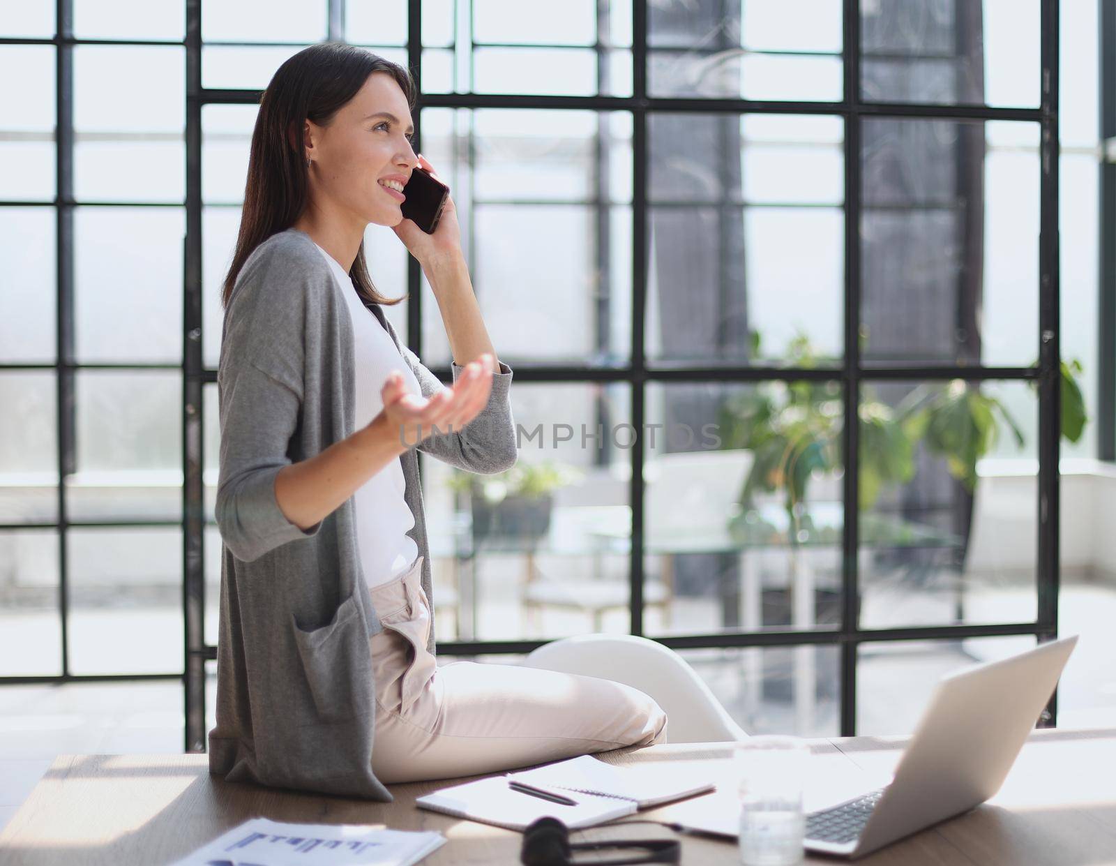 Businesswoman sitting in office, talking on the phone