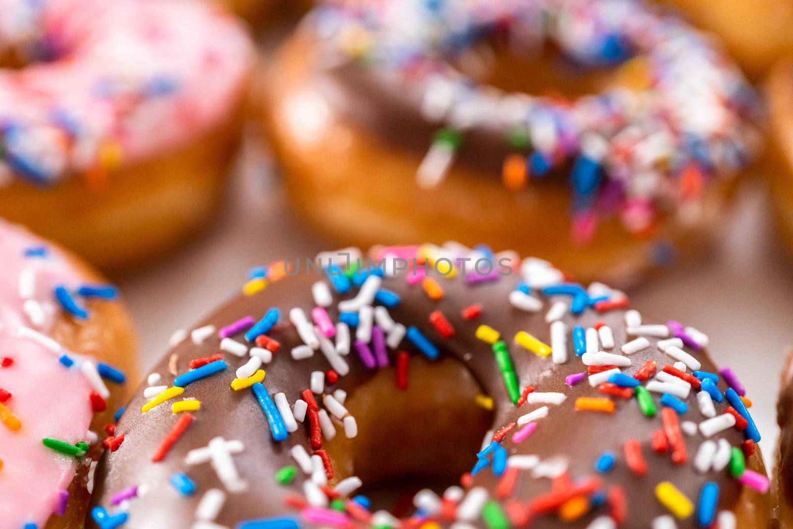 Variety of store-bought doughnuts in a white paper box.