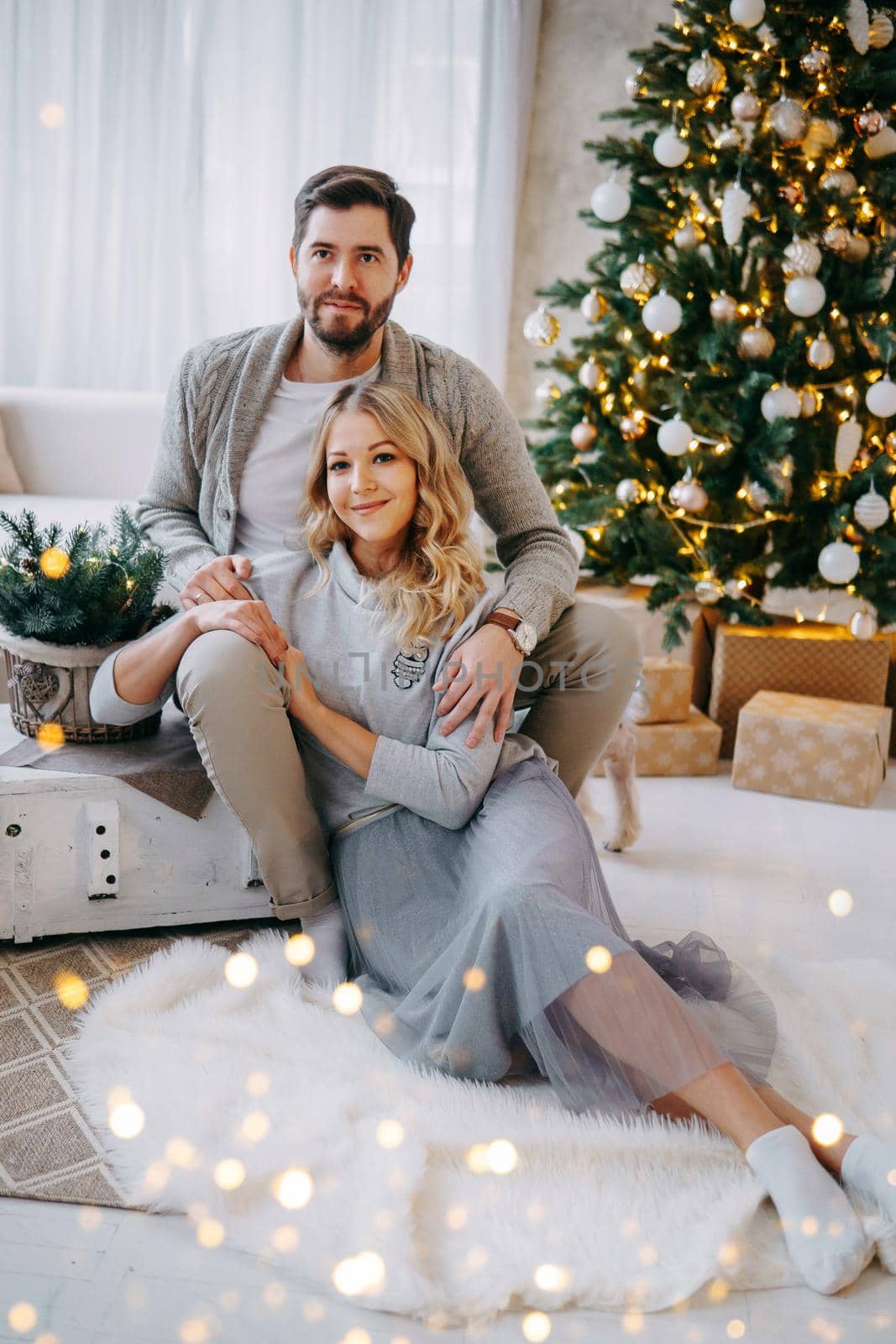 A happy couple in love - a man and a woman. A family in a bright New Year's interior with a Christmas tree.