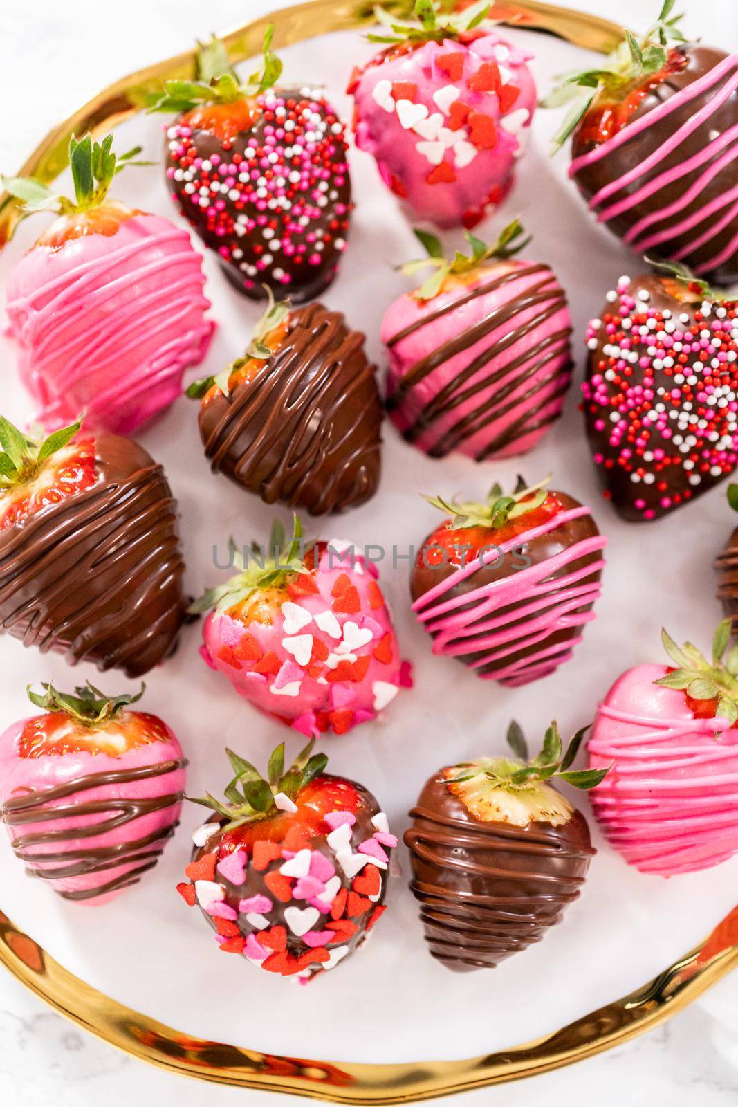 Gourmet chocolate-covered strawberries decorated with chocolate drizzles and sprinkles on a white plate.