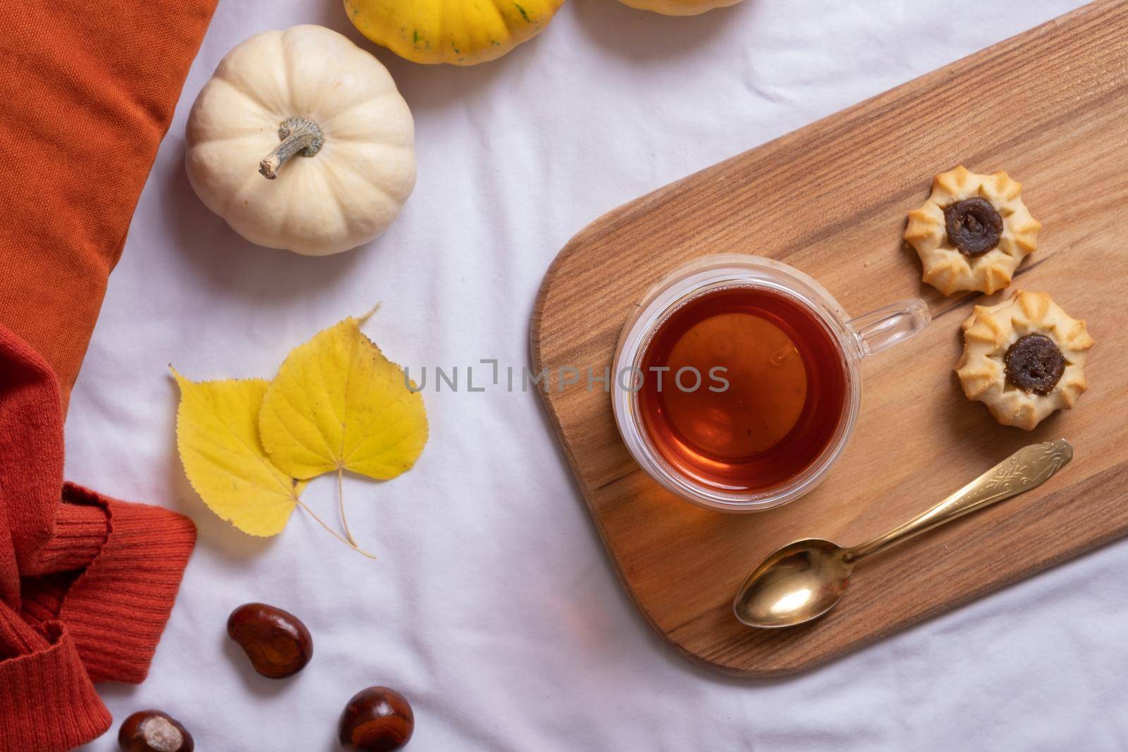 Cup of tea and autumn cozy decor with sweater and pumpkins top view.