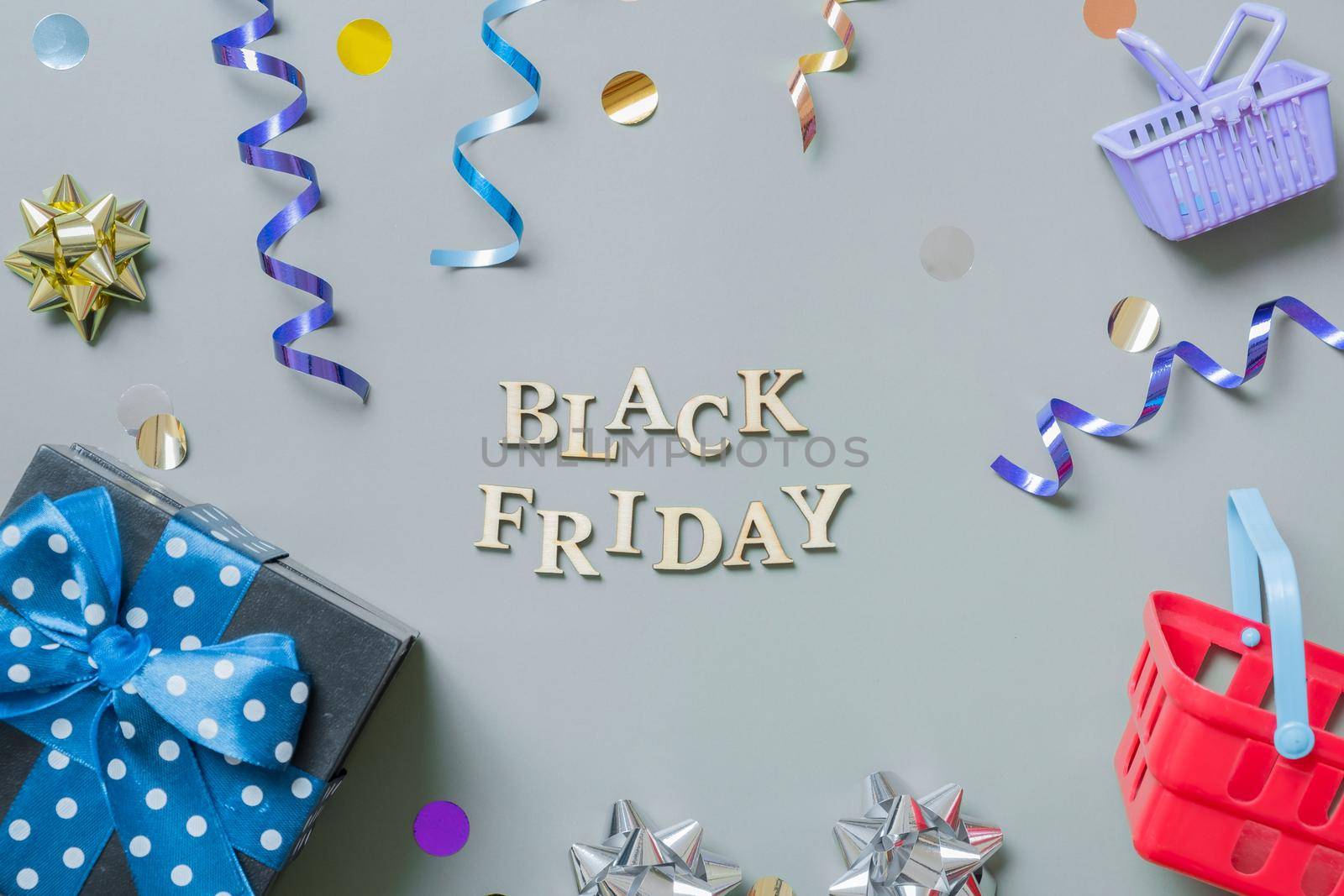 Black friday text with gifts, shopping baskets and festive tinsel flat lay.
