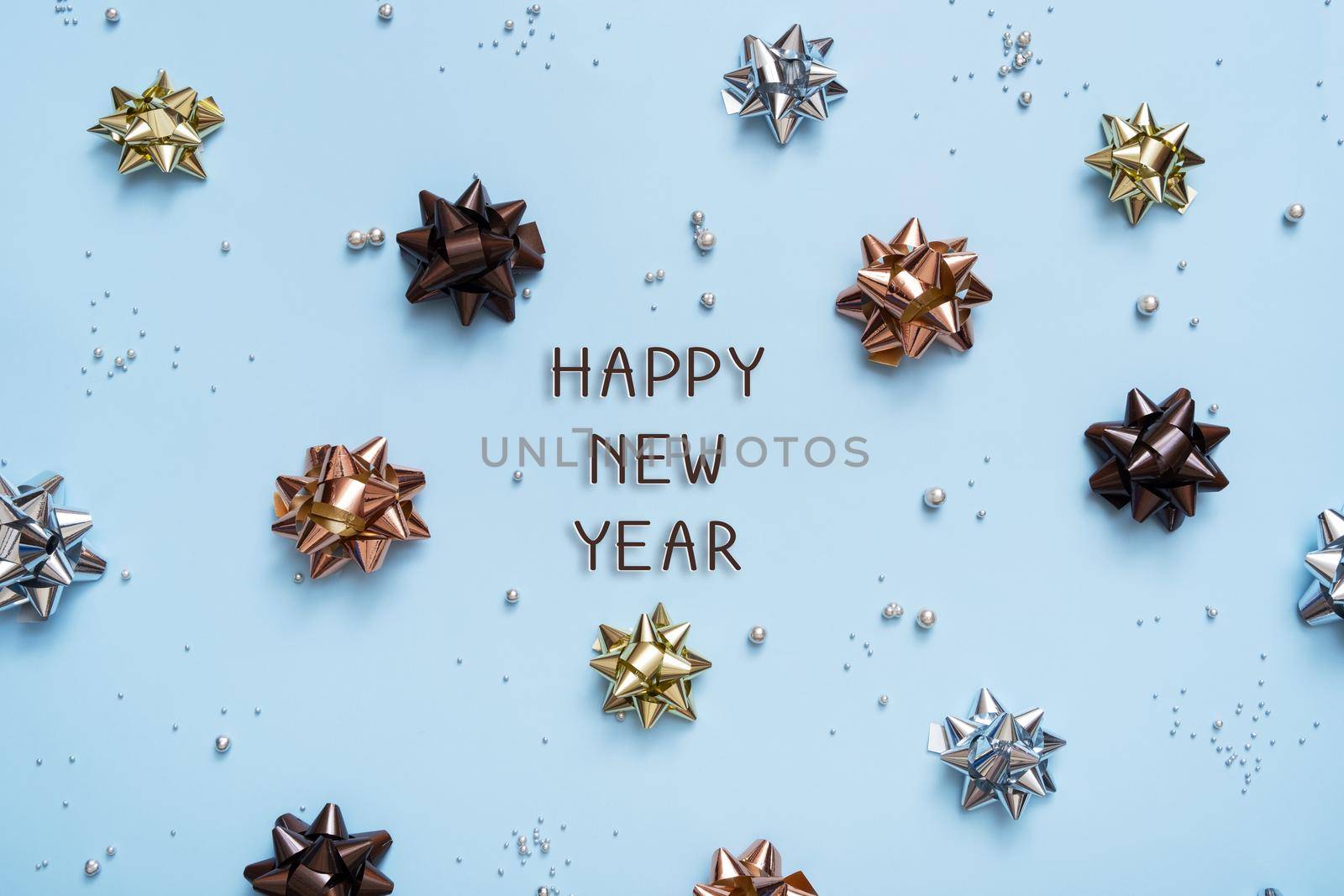 Happy Nye Year text on bright festive background with bows and beads top view. New Year background flat lay.