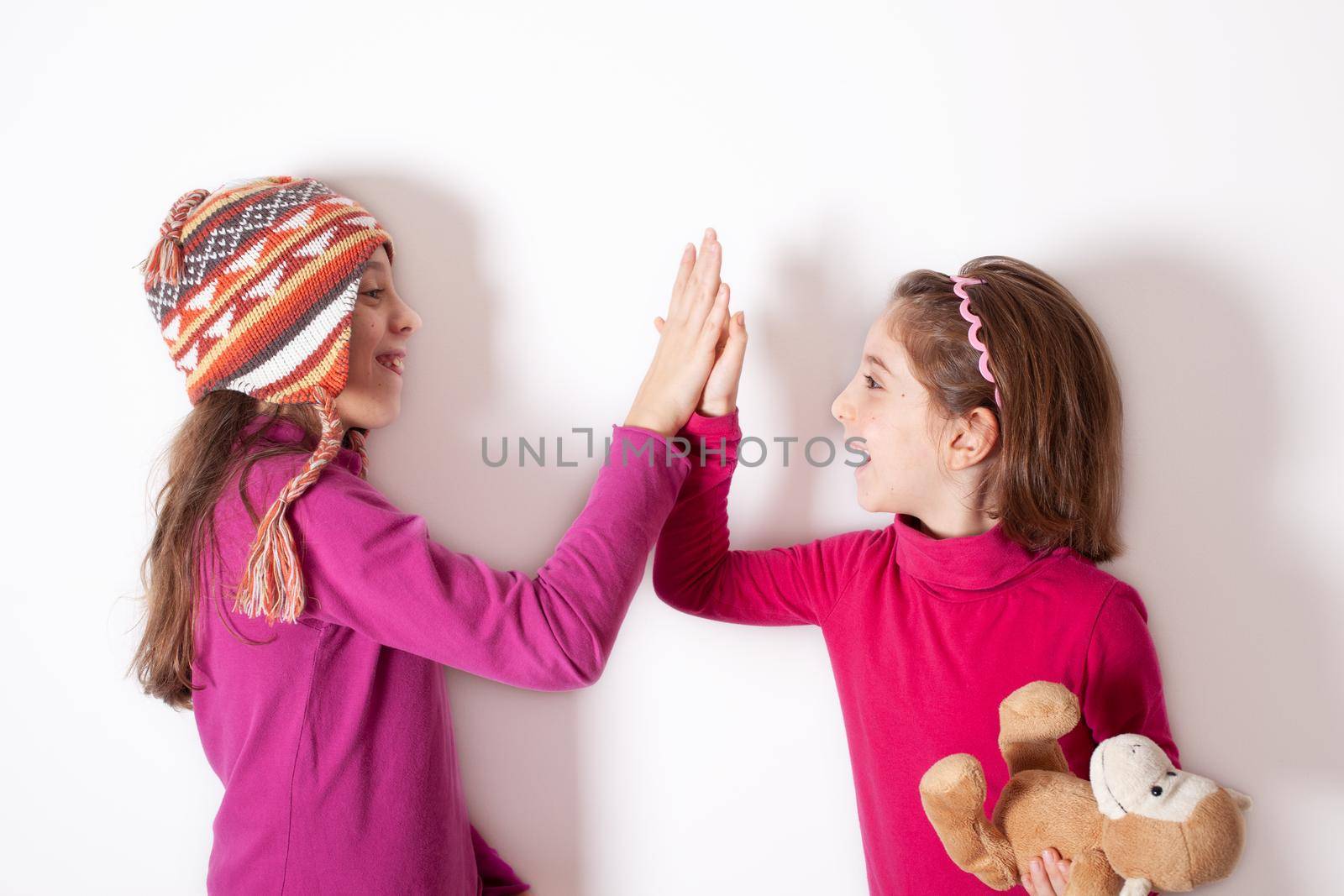 Little sisters giving high five on white by bepsimage