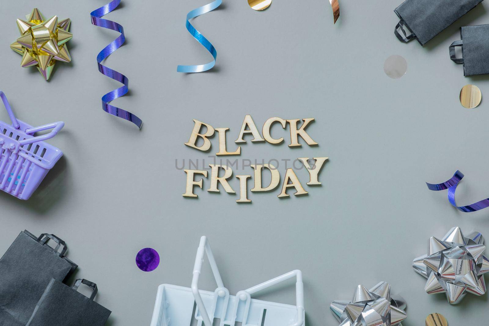 Black friday text with gifts, shopping baskets and festive tinsel flat lay.