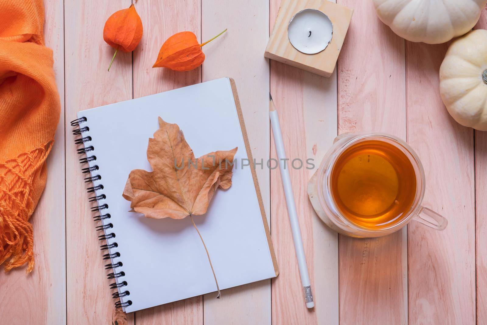 Fallen leaf and autumn cozy decor and pumpkins top view on wooden table.