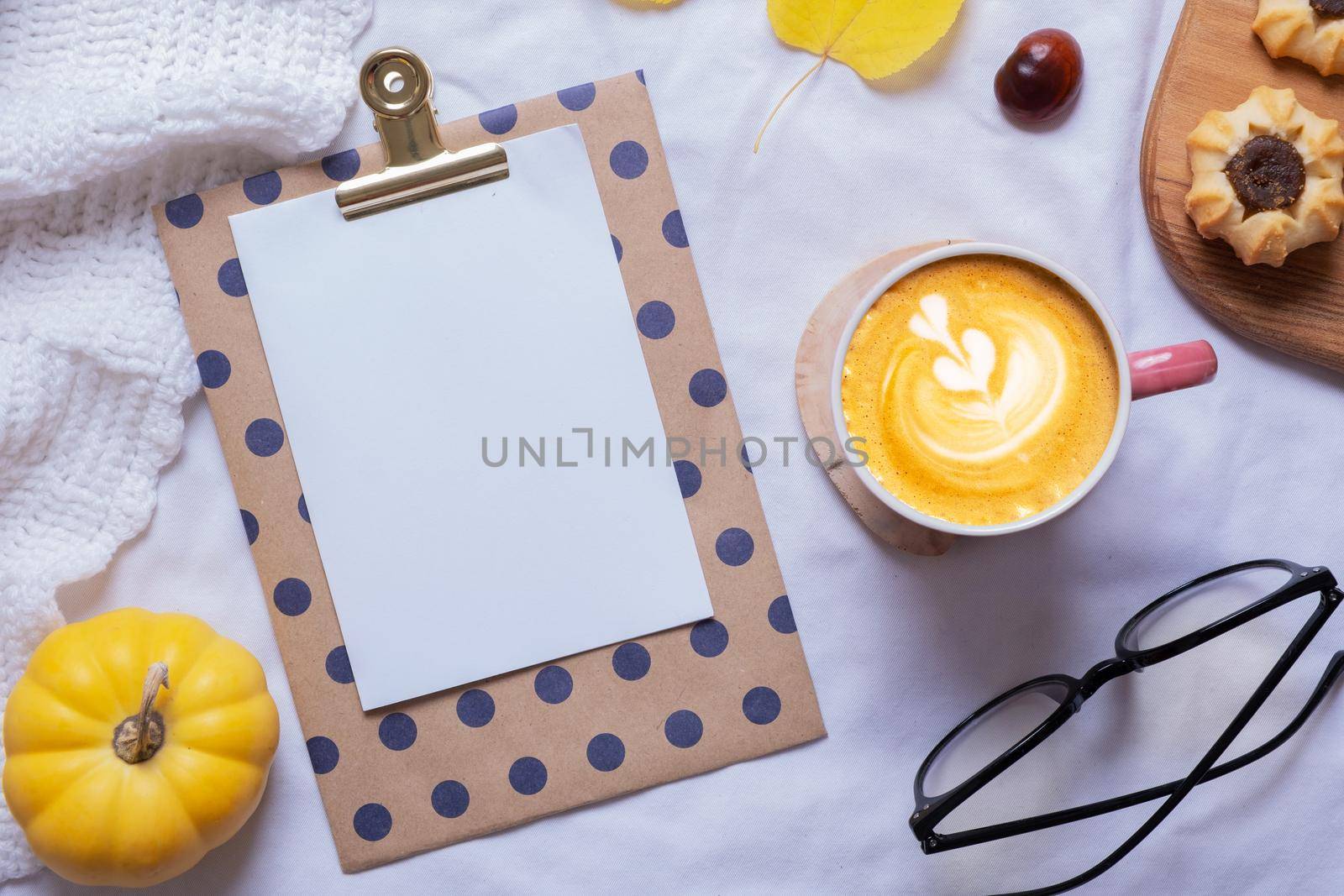 Blank sheet of paper and latte cup with autumn cozy decor top view. Copy space for autumn text.