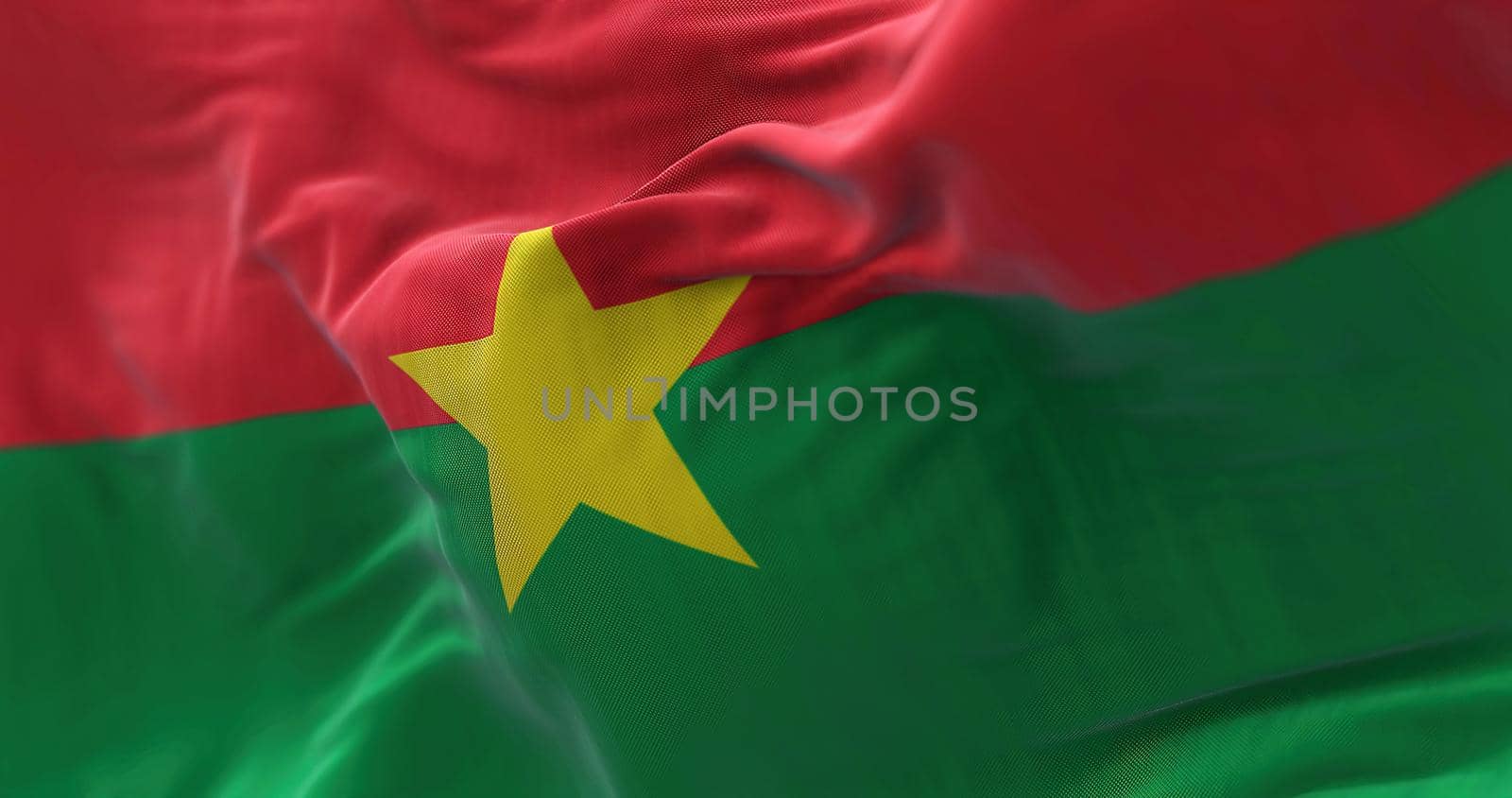 Close-up view of the Burkina Faso national flag waving in the wind. Burkina Faso is a country in West Africa. Fabric textured background. Selective focus