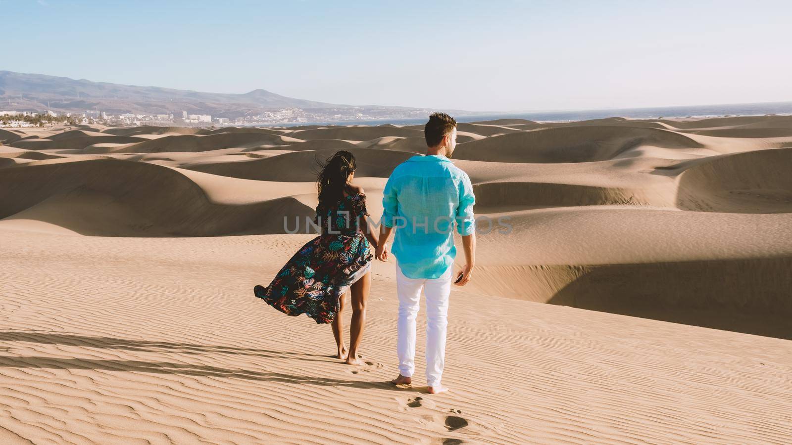 couple walking at the beach of Maspalomas Gran Canaria Spain, men and woman at the sand dunes desert of Maspalomas Gran Canaria