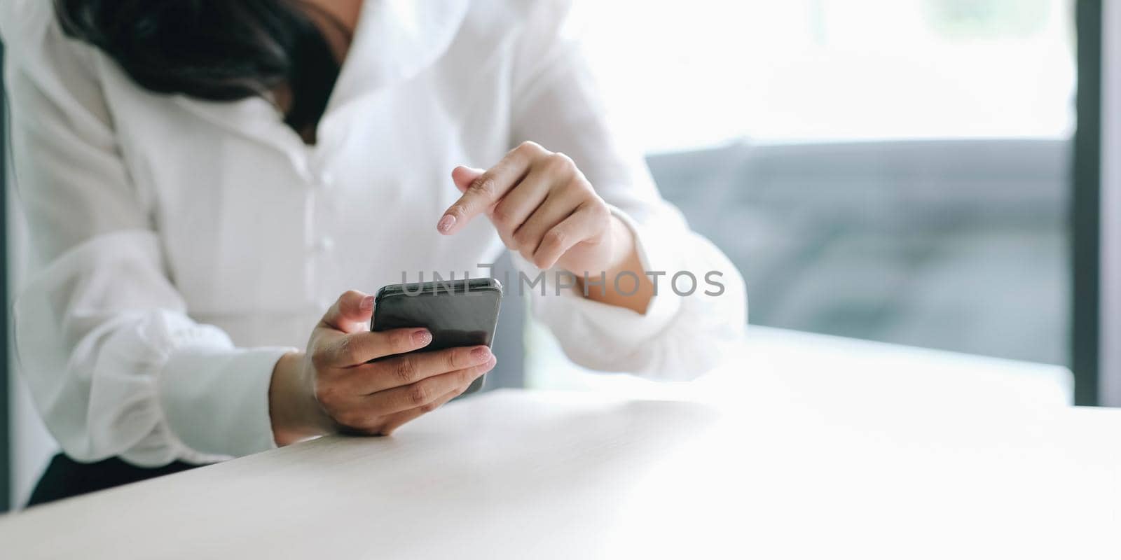 Closeup image of a beautiful asian woman holding , using and looking at smart phone by wichayada