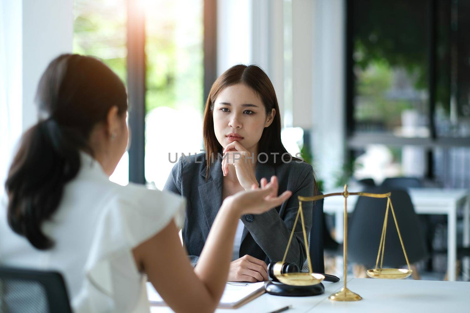 Business woman and lawyers discussing contract papers with brass scale on wooden desk in office. Law, legal services, advice, Justice concept.