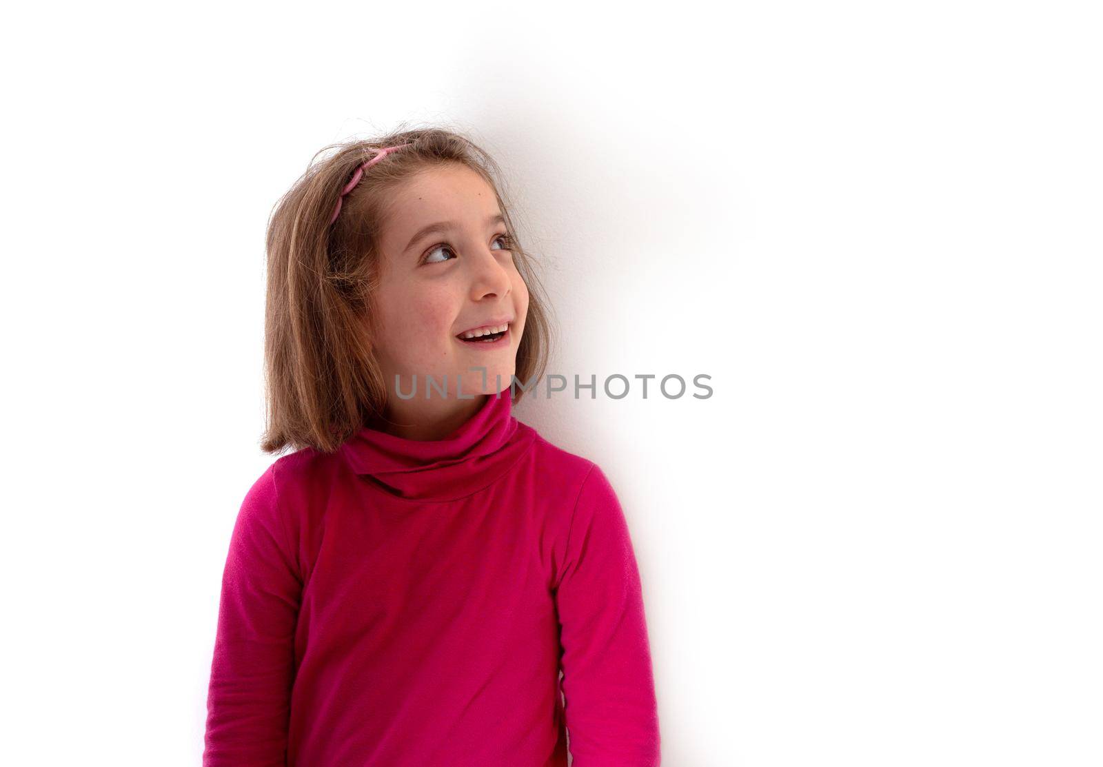 Little child girl smiling and looking up on white background by bepsimage