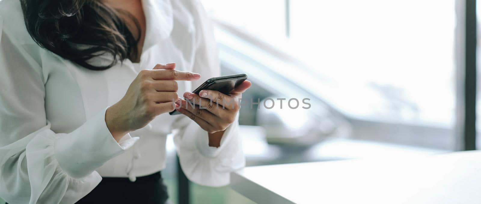 Closeup image of a beautiful asian woman holding , using and looking at smart phone.