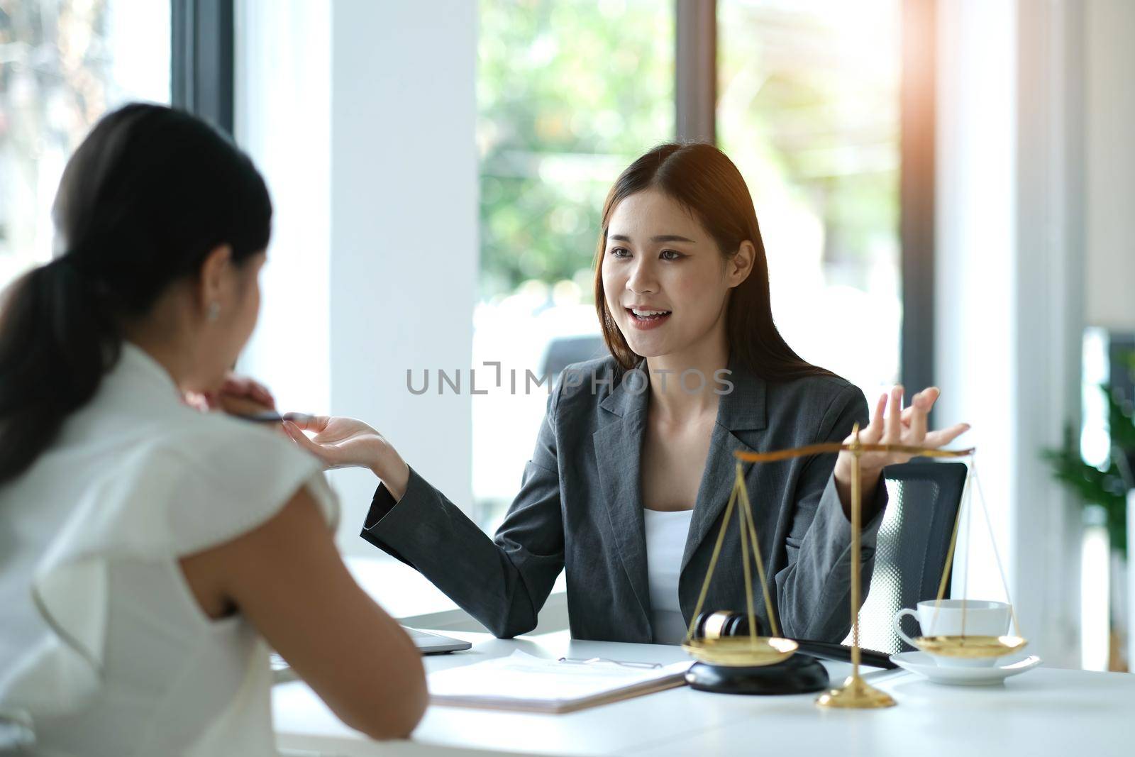 Business woman and lawyers discussing contract papers with brass scale on wooden desk in office. Law, legal services, advice, Justice concept by wichayada