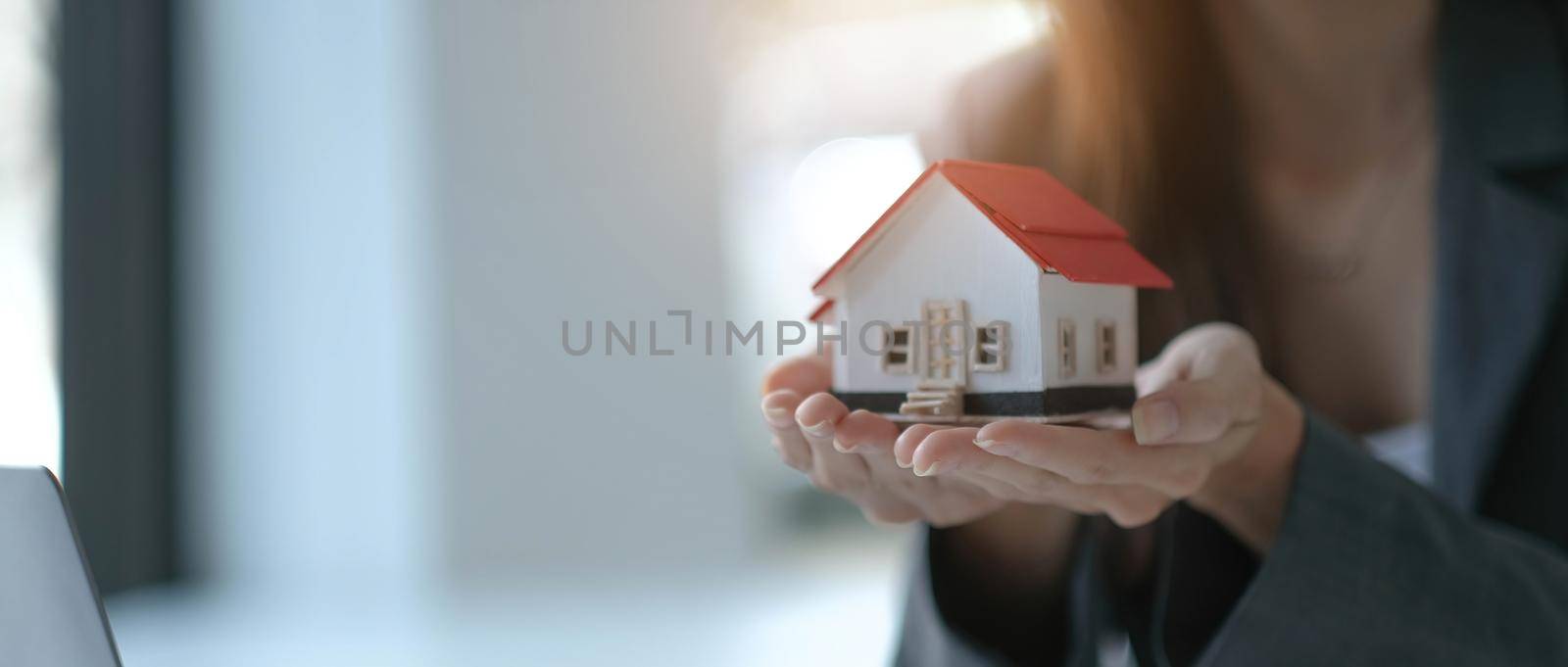 architecture, building, construction, real estate and property concept - close up of hands holding house or home model by wichayada
