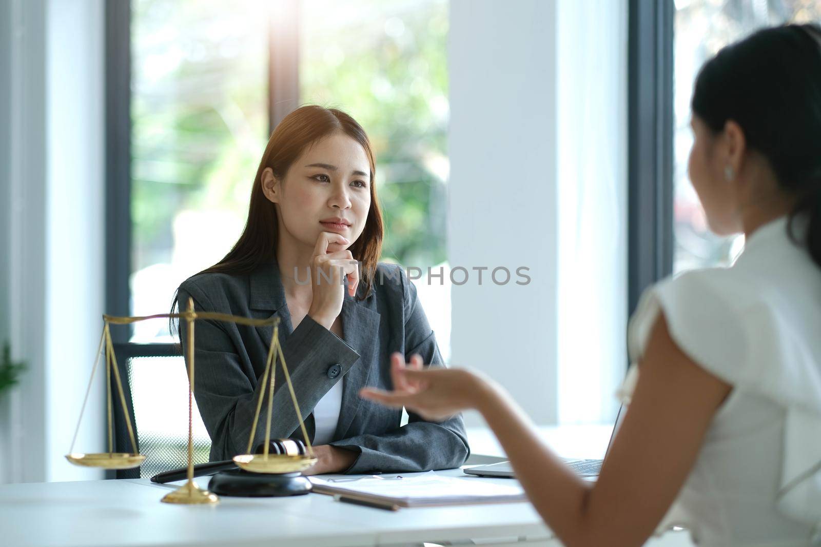 Business woman and lawyers discussing contract papers with brass scale on wooden desk in office. Law, legal services, advice, Justice concept.