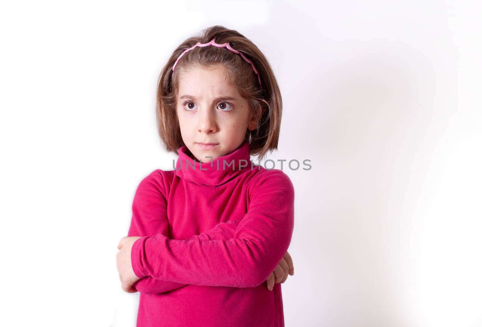 Cute upset little girl standing isolated over white background, looking away