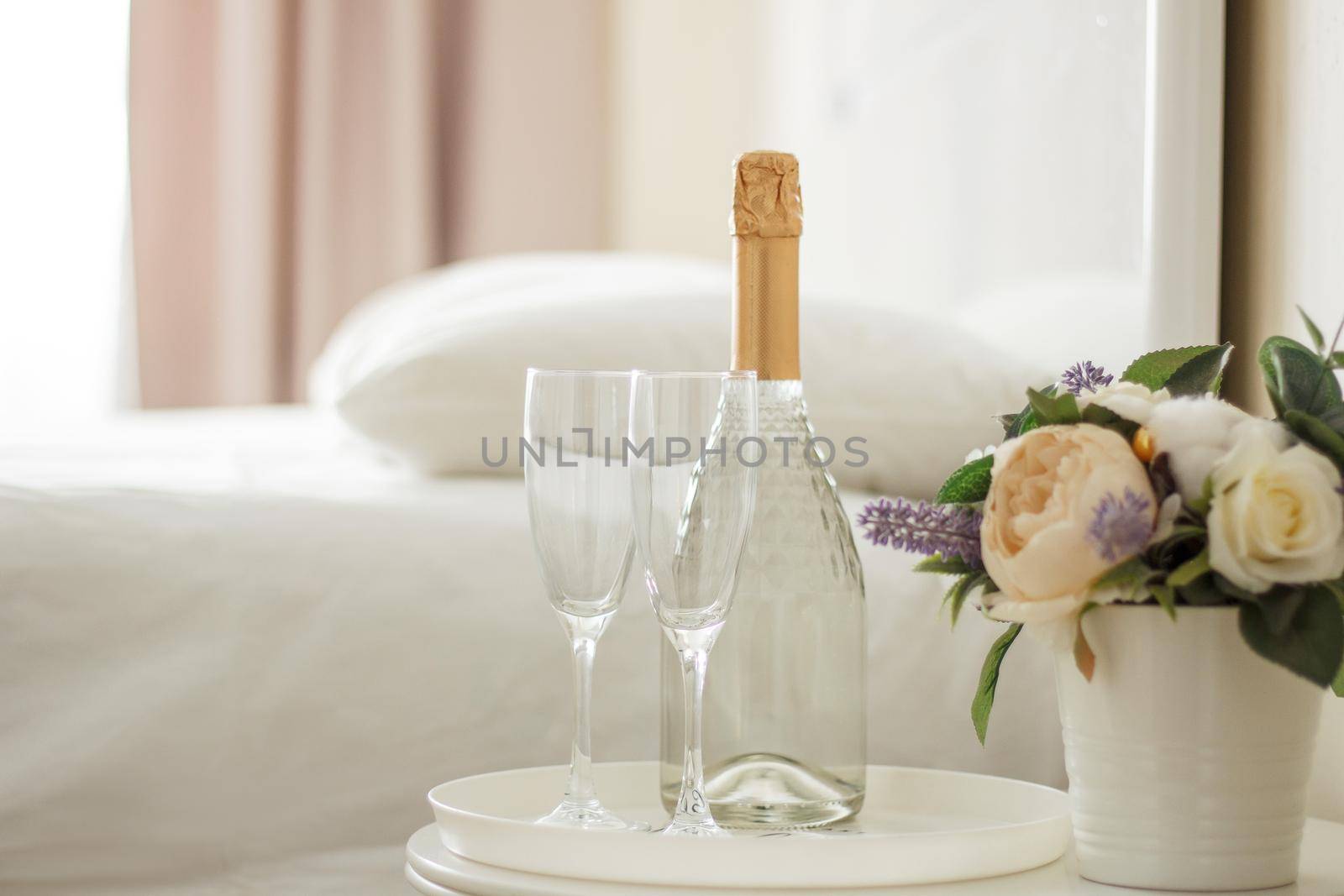 Two glasses and a bottle of champagne in a hotel room. Dating, romance, honeymoon, Valentine's day.