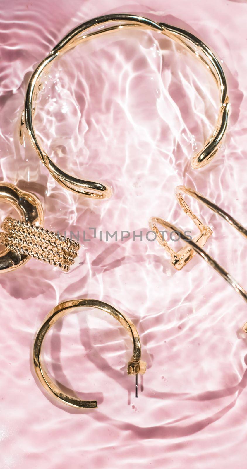 Jewellery branding, fashion gift and luxe shopping concept - Golden bracelets, earrings, rings, jewelery on pink water background, luxury glamour and holiday beauty design for jewelry brand ads