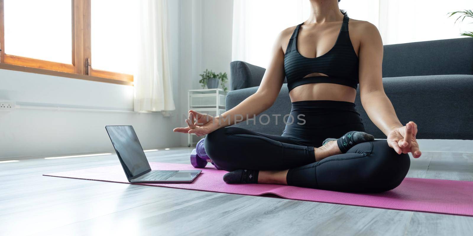 Close up of hand woman doing lotus yoga exercises on yoga mat with Training online on the tablet at home morning, Concept of relaxation and meditation by wichayada