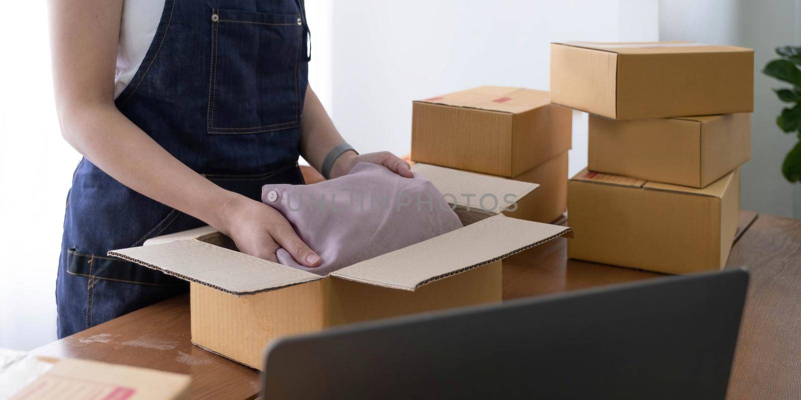 Startup small business entrepreneur SME, asian woman packing shirt in box. Portrait young Asian small business owner home office, online sell marketing delivery, SME e-commerce telemarket job concept.