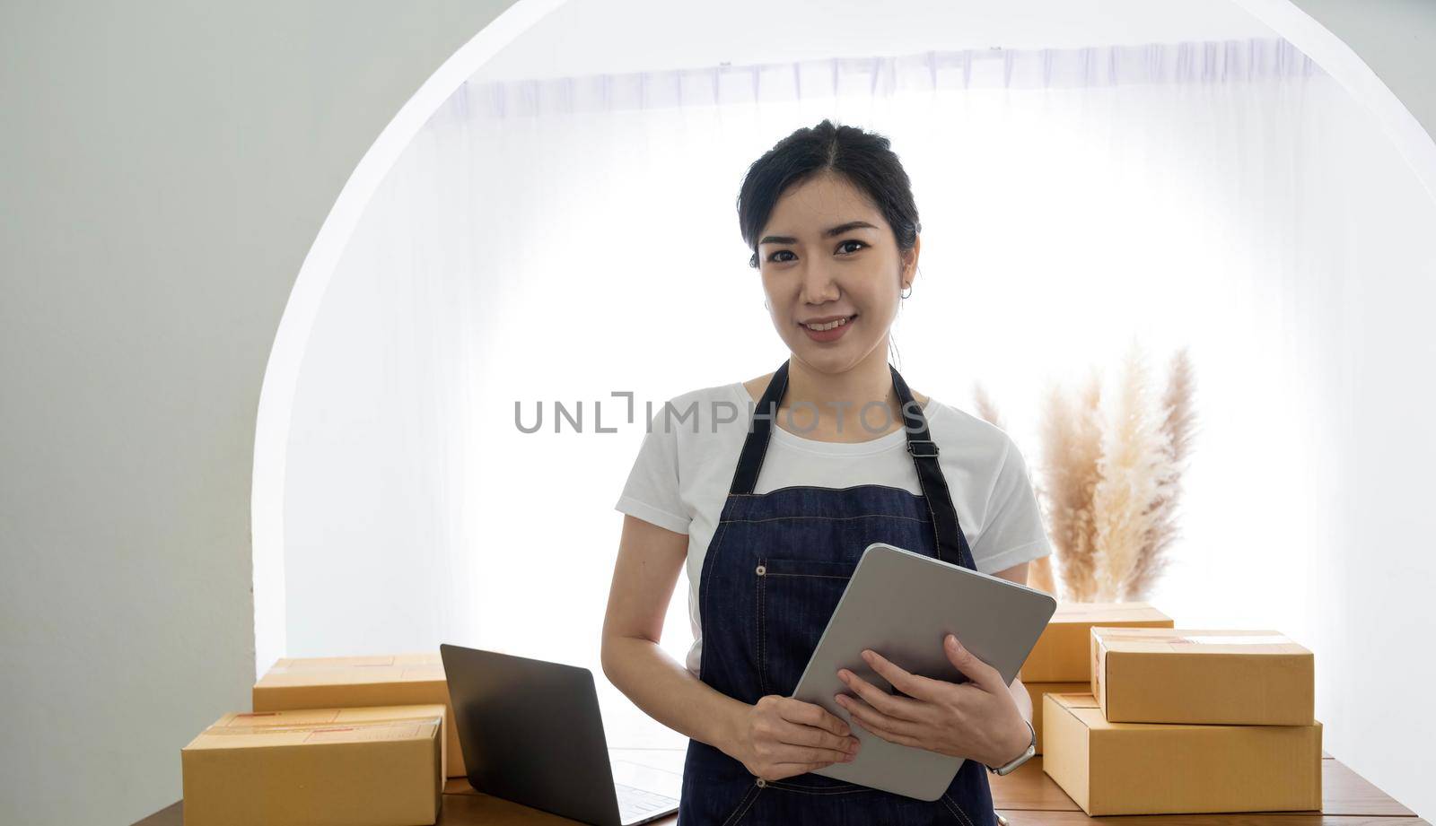 Startup SME small business entrepreneur SME or freelance Asian woman using a laptop with box, Young success Asian woman with her hand lift up, online marketing packaging box and delivery, SME concept. by wichayada