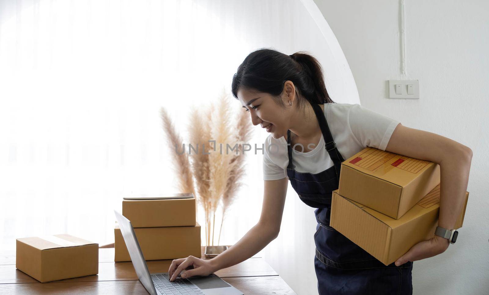 Startup happy Asian woman business owner works with a box at home, prepare parcel delivery SME supply chain, procurement, package box to deliver to customers, Online SME business entrepreneurs ideas,.