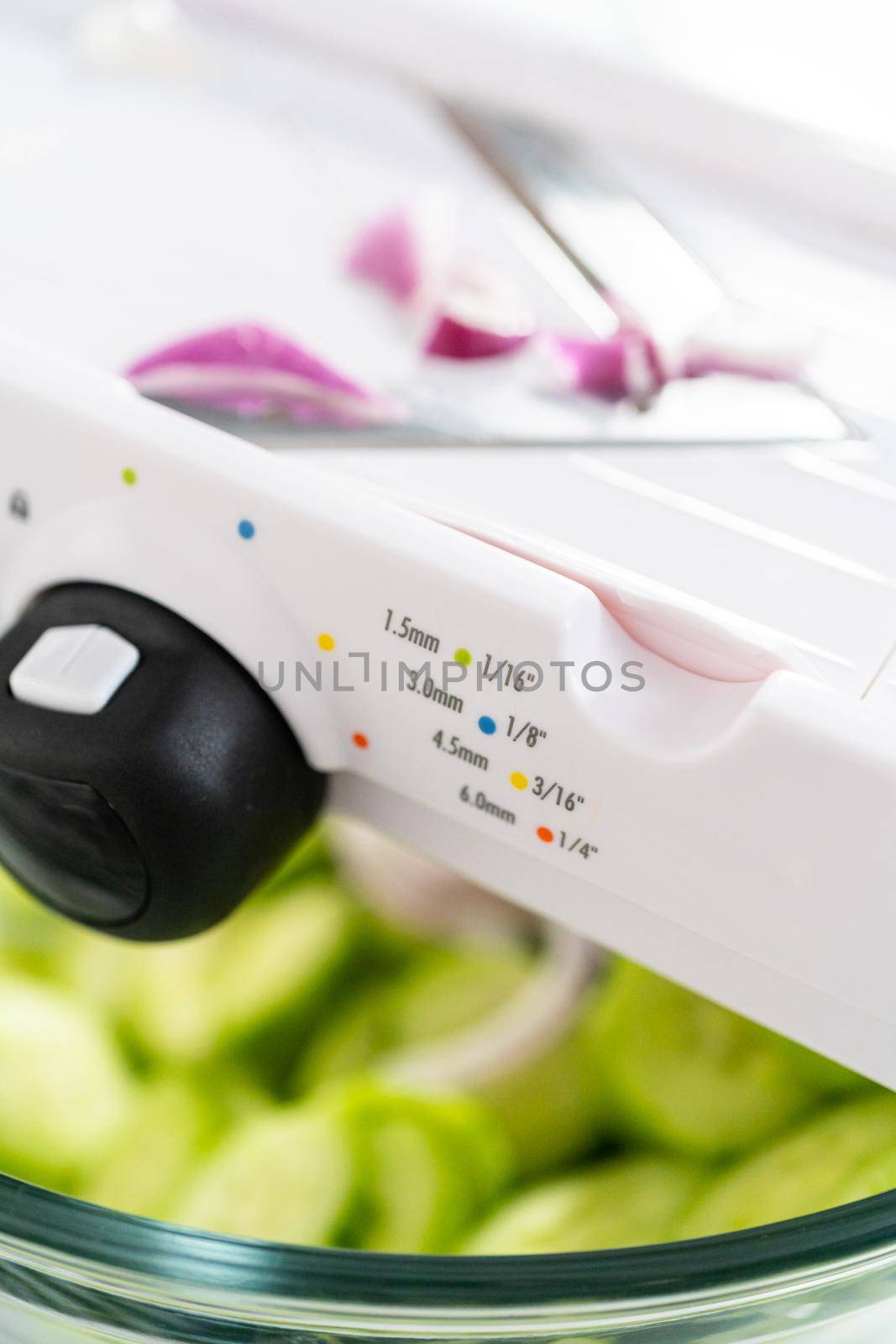 Slicing vegetables on slicer to make summer cucumber salad.